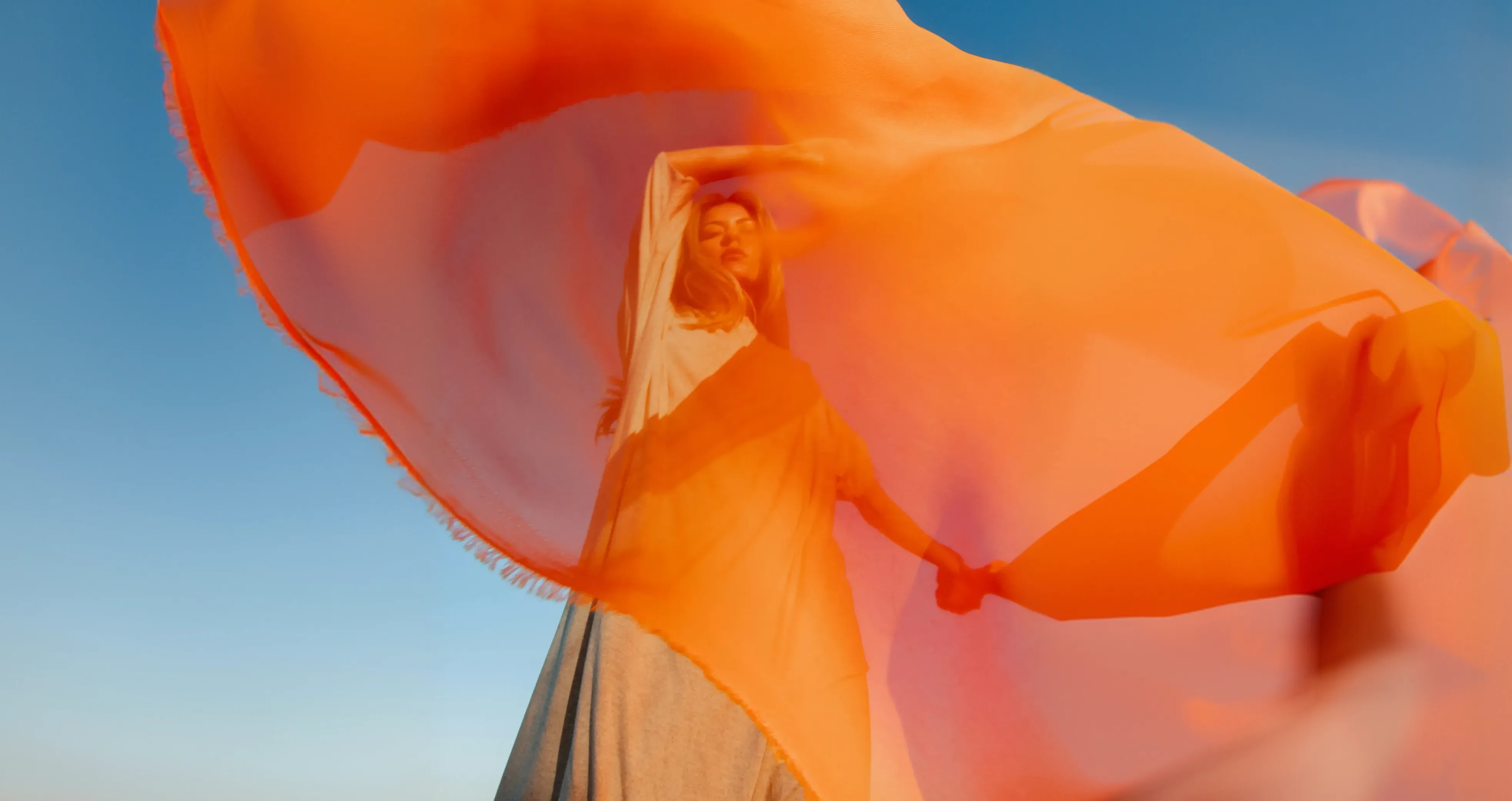 Une personne portant un tissu orange flottant au vent